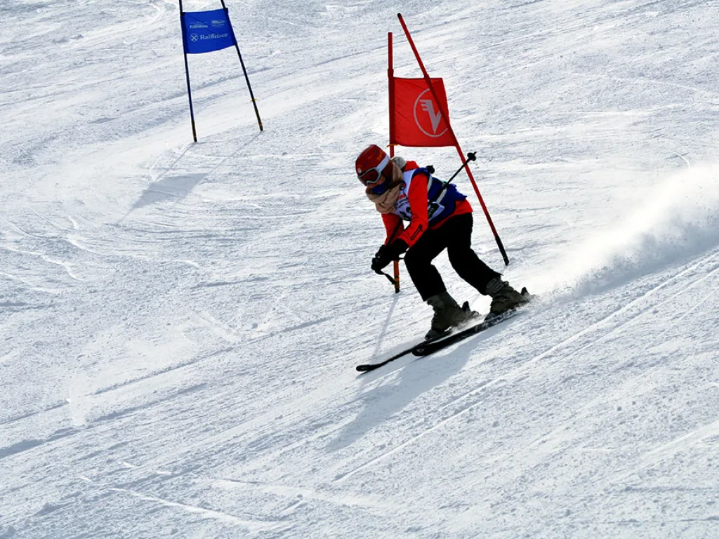 Skifahrer in roter Jacke in tiefer Hocke am Tor.